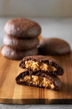 two chocolate cookies are on a cutting board with one cookie cut in half and the other half eaten