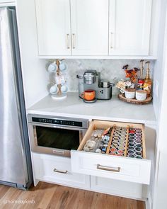 an open drawer in the middle of a kitchen with white cabinets and drawers on both sides