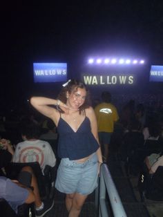 a woman standing in front of a crowd at a music festival with her arms behind her head