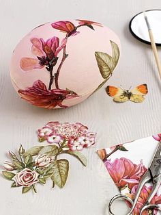 some flowers and scissors are sitting on a table next to an egg with butterflies painted on it