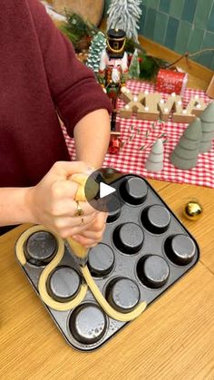 a woman is making cupcakes in a muffin tin on a table with christmas decorations