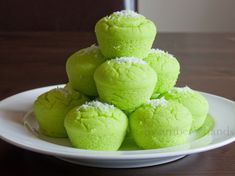 a white plate topped with green powdered donuts on top of a wooden table