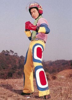 a man dressed as a person standing on top of a dry grass covered field with his hands in his pockets