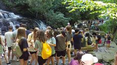 a group of people standing in front of a waterfall