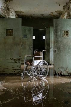 a wheelchair sitting in the middle of a room with peeling paint on the walls and floor