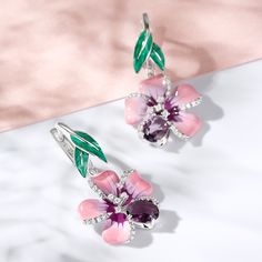 Creating a refreshing appeal with its delicate floral design, this pair of enamel earrings is a masterpiece in itself. These lovely earrings embody the youth of flowers and the freshness of spring. Pink and purple flowers and green enamel leaves are adorned with purple oval-cut stones and white round-cut stones in polished sterling silver. Pair it up with a pretty floral print dress and you're good to go for a happening day out or at a party.Carat Weight: 0.63 ctStone Shape: RoundStone Size: 1,1 Elegant Enamel Flower Earrings, Pink Enamel Flower-shaped Earrings, Elegant Flower Shaped Enamel Earrings, Elegant Enamel Drop Flower Earrings, Elegant Spring Flower Earrings With Floral Print, Elegant Floral Print Earrings For Spring, Elegant Floral Print Flower Earrings For Spring, Pink Flower-shaped Enamel Earrings, Pink Flower Enamel Earrings