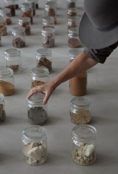 a person reaching for something in a jar filled with dirt and rocks on the ground