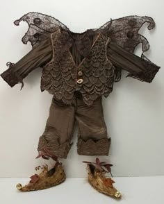 an old doll with lace on it's jacket and shoes is sitting in front of a white wall