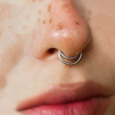 a woman's nose with an open nose ring on top of her nose,