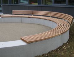 a curved wooden bench sitting in front of a building