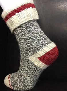 a pair of gray and red socks sitting on top of a black leather couch next to a white vase