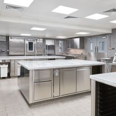 an empty kitchen with stainless steel appliances and white marble counter tops, is pictured in this image