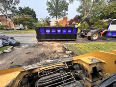 a dump truck is parked next to a pile of rubble and other debris on the street