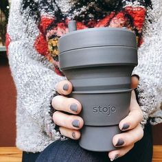 a woman holding a coffee cup with her hands on the top and bottom of it