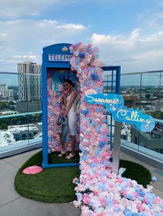 a woman standing in a phone booth made out of flowers