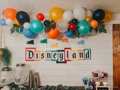 balloons and streamers are hanging from the ceiling in front of a sign that says disneyland land