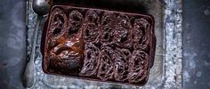 a chocolate cake sitting on top of a metal pan next to a fork and spoon