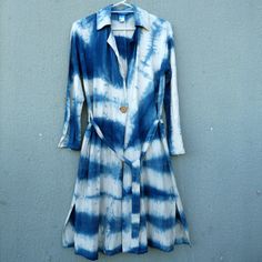 a blue and white tie - dyed dress hanging on a wall with a button up shirt underneath it