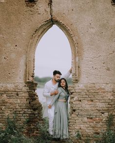 a man and woman standing next to each other in front of an old building