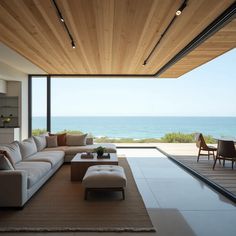 a living room with couches and tables in front of the ocean