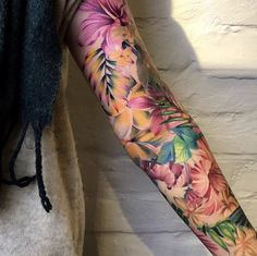 a woman's arm with flowers and leaves on it