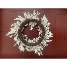 a wreath with white flowers hanging on a red door