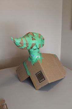 a cardboard box with a green dinosaur head on top of it sitting on a table