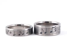 two wedding bands with musical notes on them, one is silver and the other is black