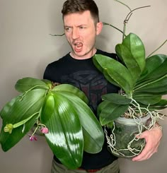 a man holding a potted plant in front of his face and making a surprised face