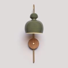 a green wall mounted light with a wooden base and round shade on the back of it