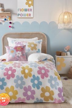 a bed with colorful flowers on it in a child's bedroom, the comforter is pink and blue