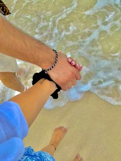 two people holding hands while standing on the beach