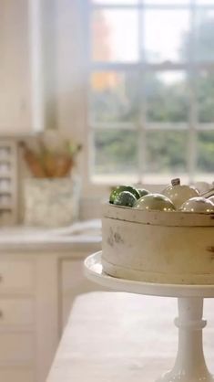 a white cake sitting on top of a table in a kitchen next to a window