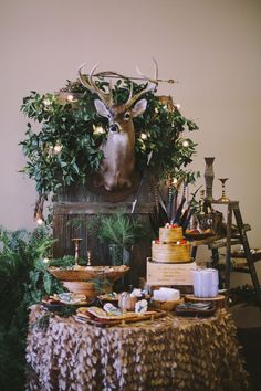 a table topped with lots of food next to a deer head