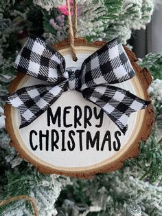 a christmas ornament hanging on a tree with the words merry christmas in black and white