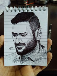 a drawing of a man's face is shown on a notepad with a pen