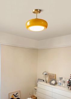 a living room with white furniture and a yellow light hanging over the top of it