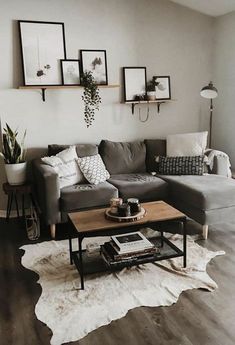 a living room with gray couches and pictures on the wall above it's coffee table