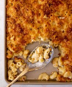 macaroni and cheese casserole in a pan with a spoon on the side