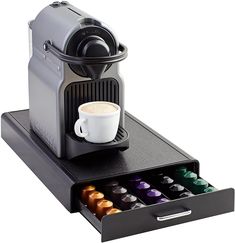 an espresso machine with its drawer open and coffee cup in the bottom compartment