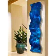 a blue vase sitting on top of a counter next to a wall mounted art piece