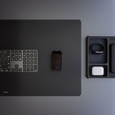 a computer keyboard and mouse sitting on top of a black table next to other items