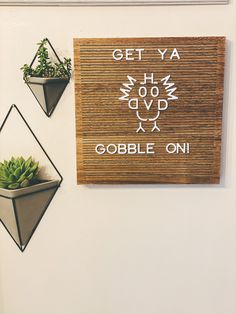 two hanging planters on the wall with plants in them and a sign that says get ya gobble on