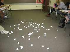 several people sitting at desks with papers scattered on the floor