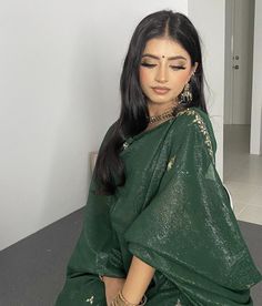 a woman sitting on the floor in a green sari