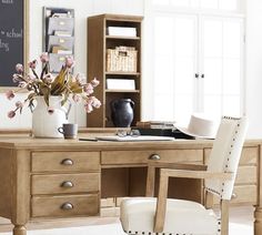 a wooden desk topped with a white vase filled with flowers