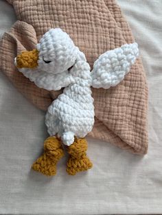 a crocheted stuffed animal laying on top of a bed next to a blanket