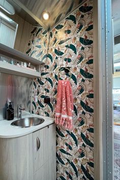 a kitchen area with sink, cabinets and wallpapered walls in an rv or boat