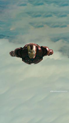 the iron man is flying through the air above the clouds in his suit and helmet