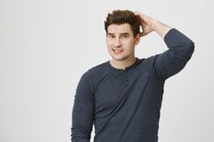 a young man is holding his hair in one hand and looking at the camera while standing against a white background